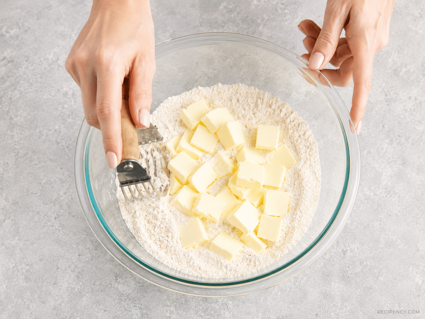 Cold cubed butter being cut into flour and sugar with a pastry blender