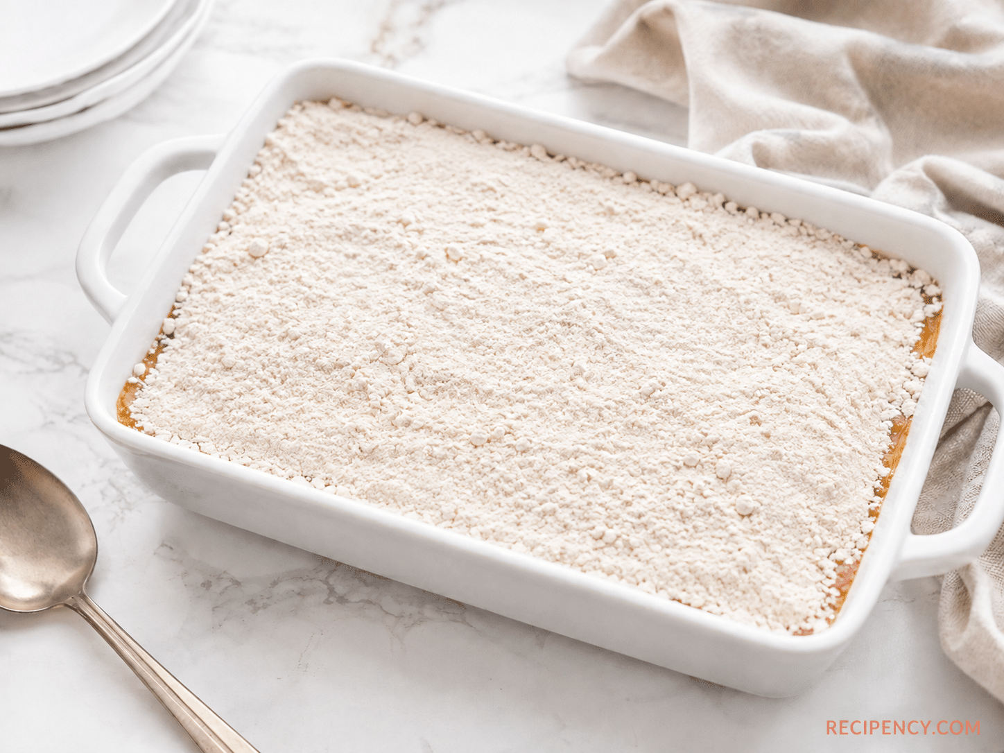 Dry vanilla cake mix evenly distributed over the peach and cinnamon layer