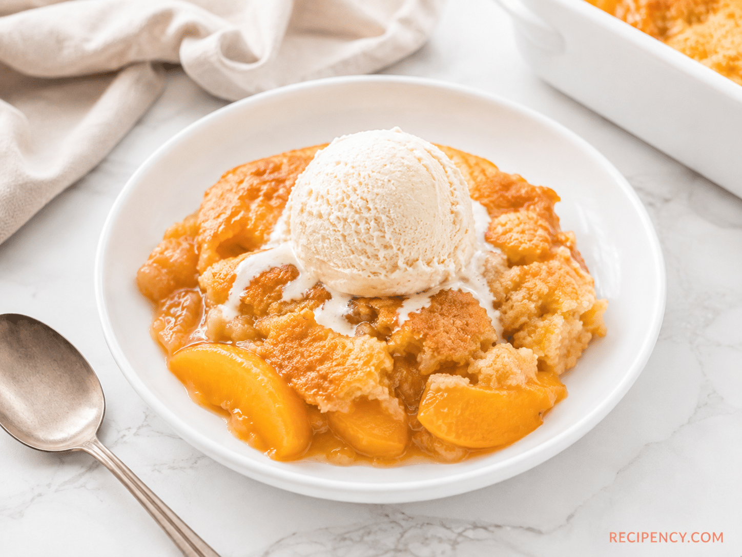 Peach Cobbler with Cake Mix topped with vanilla ice cream and a fork