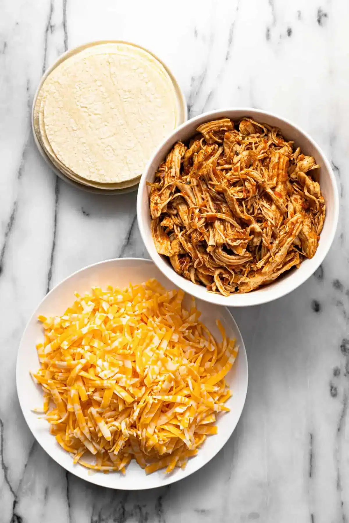20-Minute Mini Tacos (Crispy Baked Chicken Tacos) 12 Bowls of seasoned shredded chicken, cheese, and corn tortillas on a marble countertop