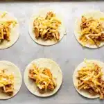 20-Minute Mini Tacos (Crispy Baked Chicken Tacos) 19 Unbaked Mini Tacos filled with seasoned chicken and shredded cheese on a metal baking sheet