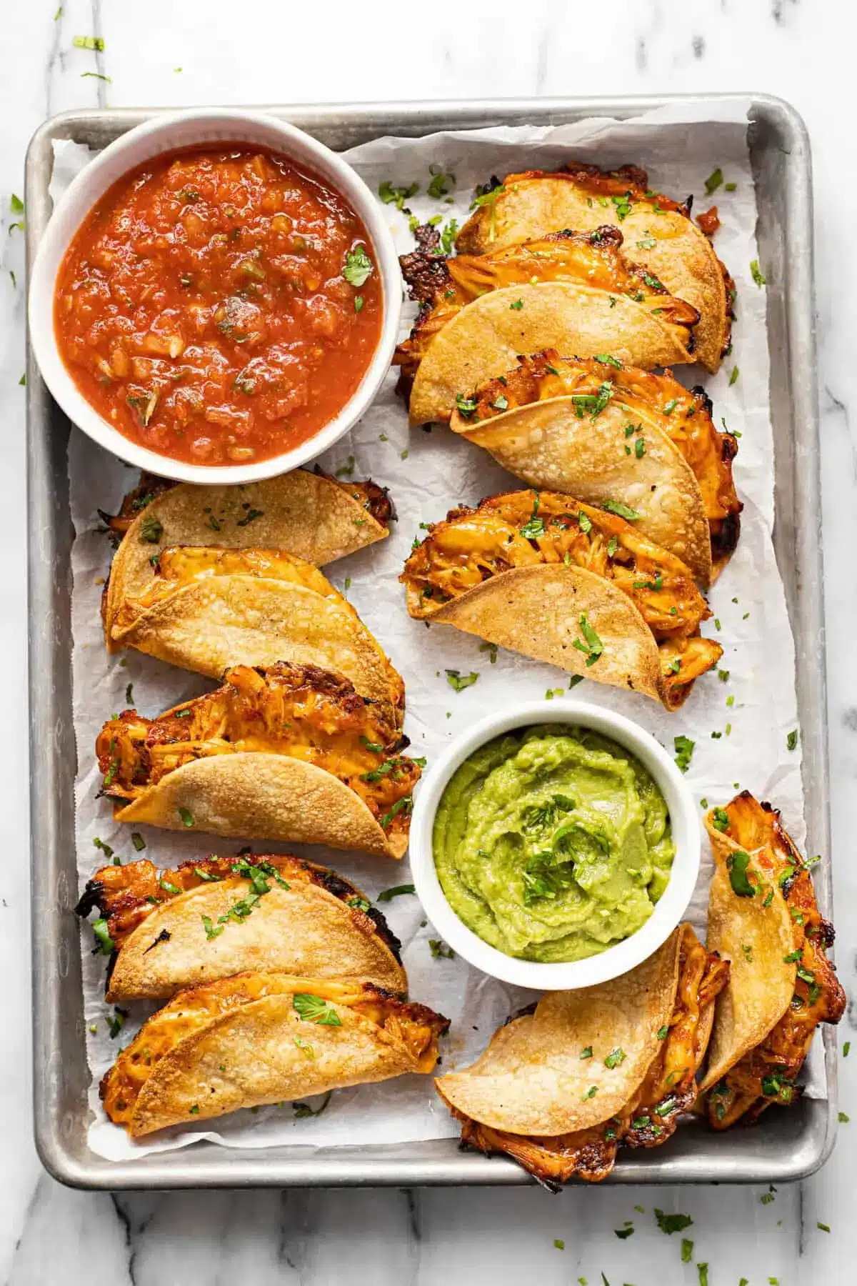 20-Minute Mini Tacos (Crispy Baked Chicken Tacos) 18 Baking sheet of Mini Tacos surrounded by bowls of guacamole and salsa
