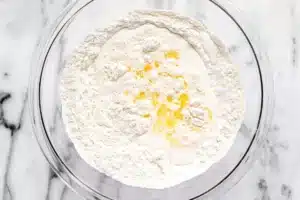 A glass mixing bowl containing combined dry ingredients for the Copycat Taco Bell Chalupa Supreme dough.