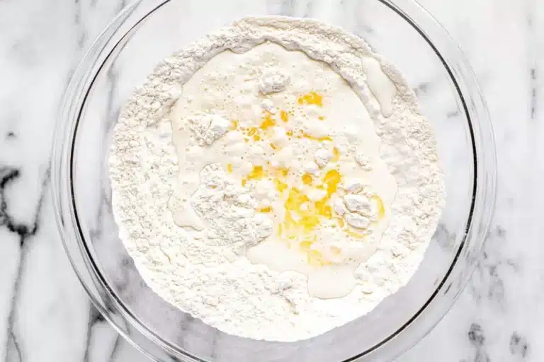 A glass mixing bowl containing combined dry ingredients for the Copycat Taco Bell Chalupa Supreme dough.