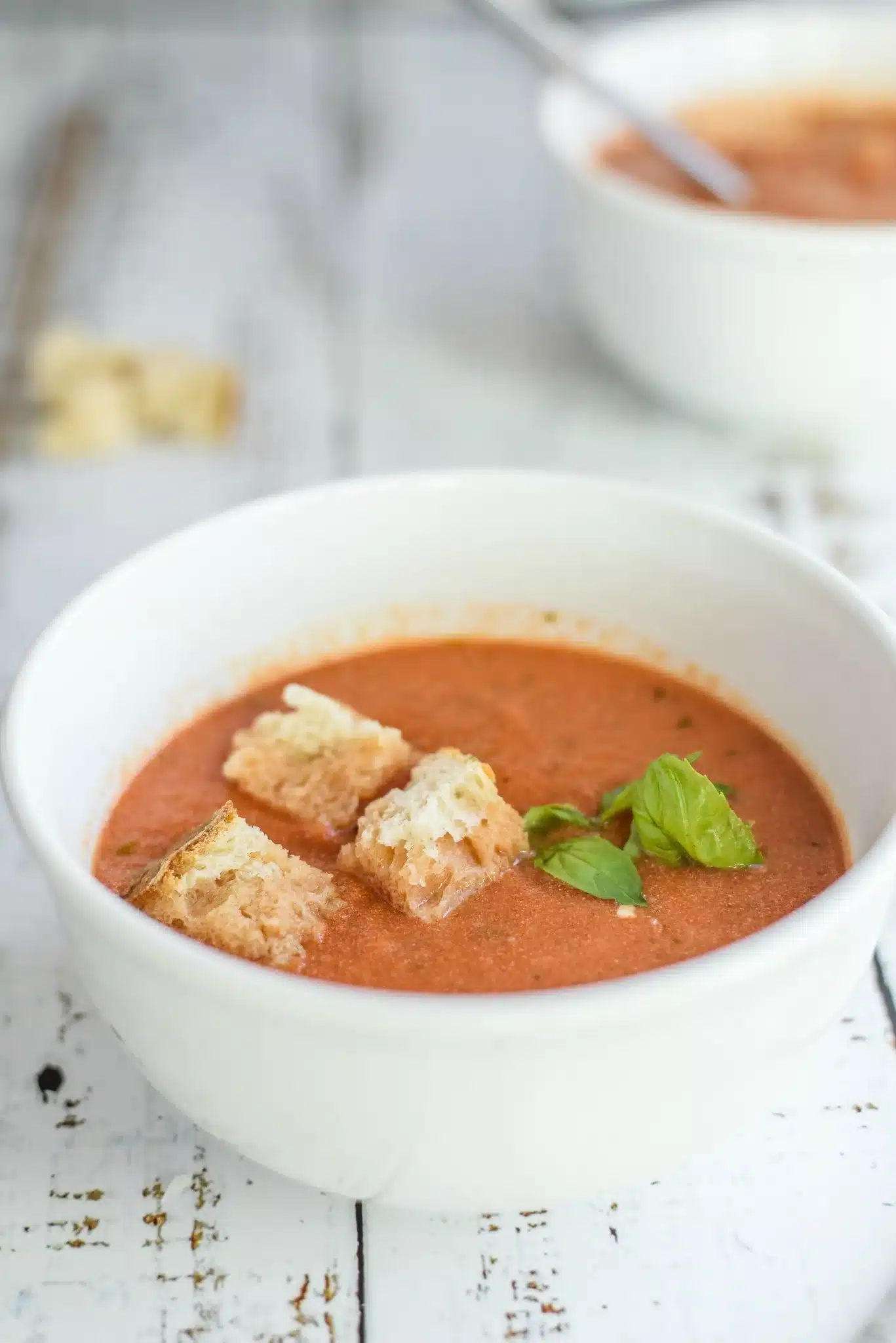 Tomato Basil Soup 7 A steaming bowl of creamy Tomato Basil Soup garnished with fresh basil leaves and grated Parmesan cheese.