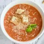 Tomato Basil Soup 11 Close-up view of homemade Tomato Basil Soup with croutons and a spoon resting in the bowl.