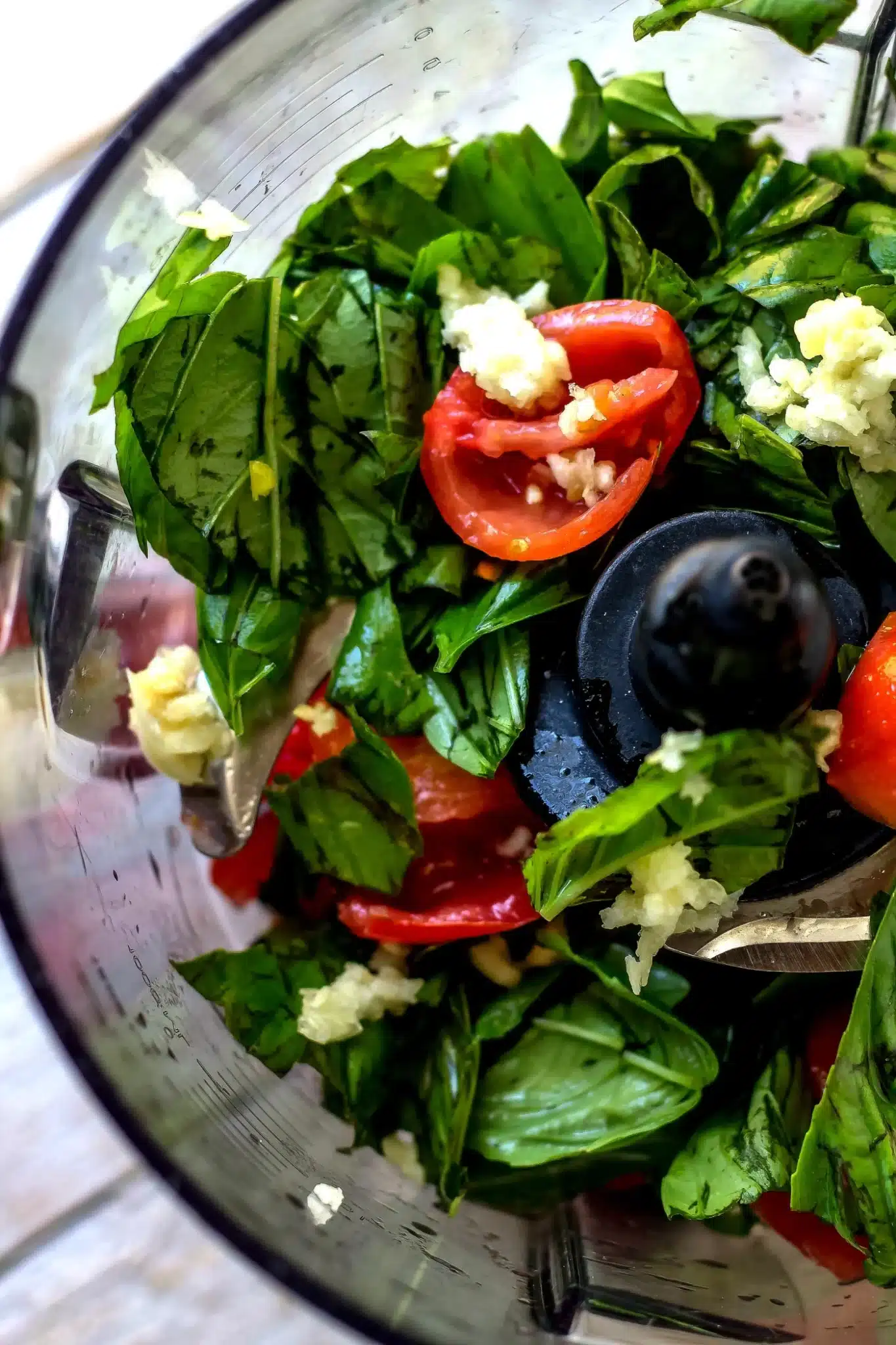 Blender containing tomatoes, basil, vinegar, and oil being processed into Tomato Basil Vinaigrette
