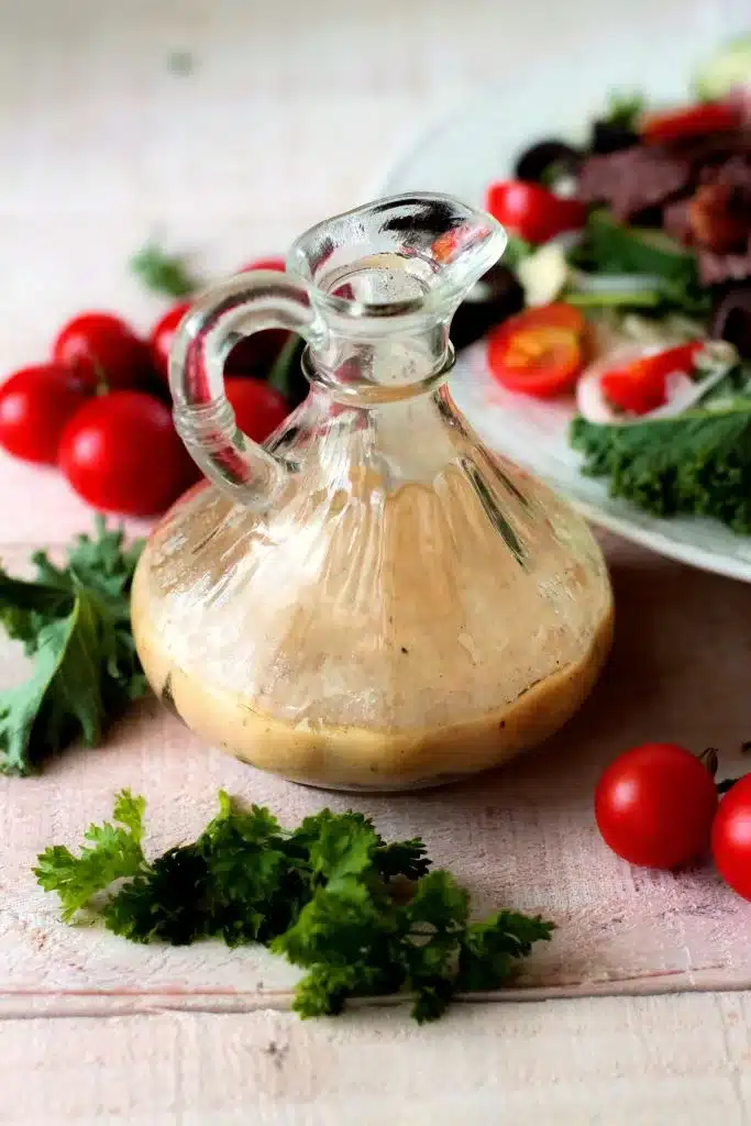 A bottle of creamy Mustard Vinaigrette alongside Dijon mustard and herbs